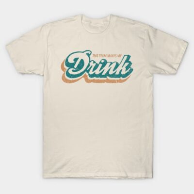 White cotton t-shirt with "This Team Makes Me Drink" graphic in vintage-style teal and orange text. Casual wear.