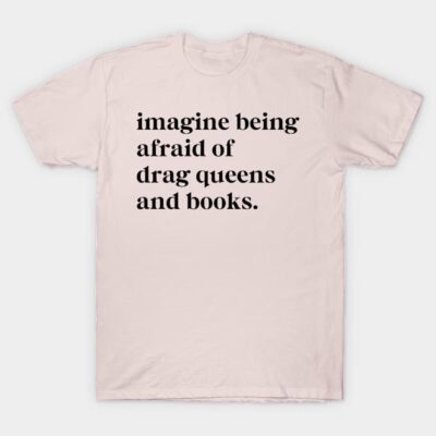 Pale pink T-shirt with bold black text saying "Imagine being afraid of drag queens and books," casual unisex style.