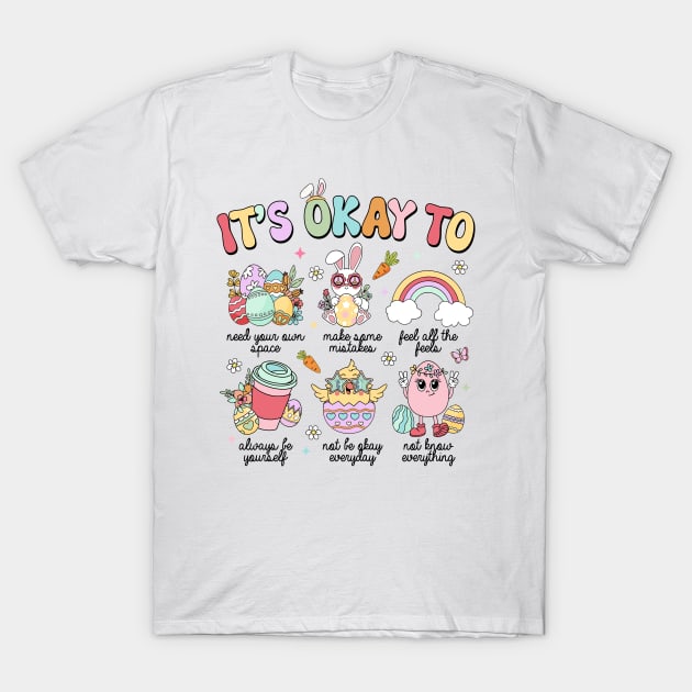 White t-shirt with colorful "It's Okay To" motivational graphics, casual style, perfect for everyday wear.
