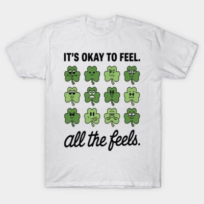White T-shirt with green shamrock emoticons and "It's Okay to Feel All the Feels" text, casual cotton top.