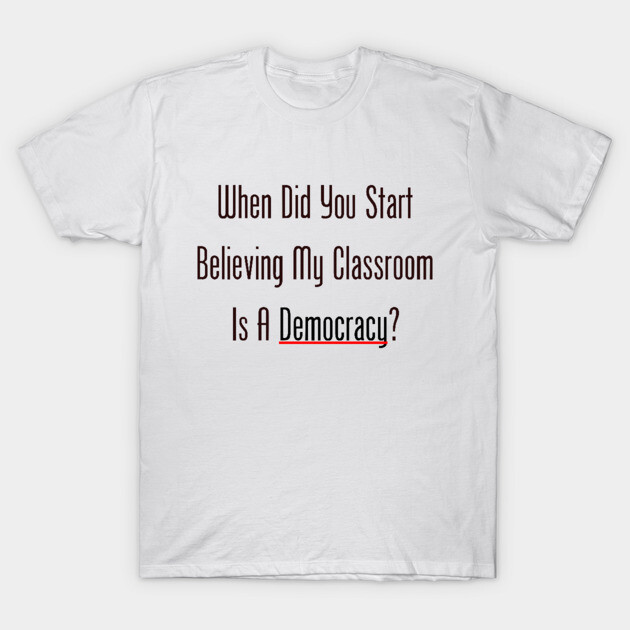 White t-shirt with "When Did You Start Believing My Classroom Is A Democracy?" printed in bold black text. Casual style.