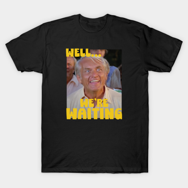Black t-shirt with humorous "Well... We're Waiting" graphic, featuring bold yellow text, casual wear, cotton material.