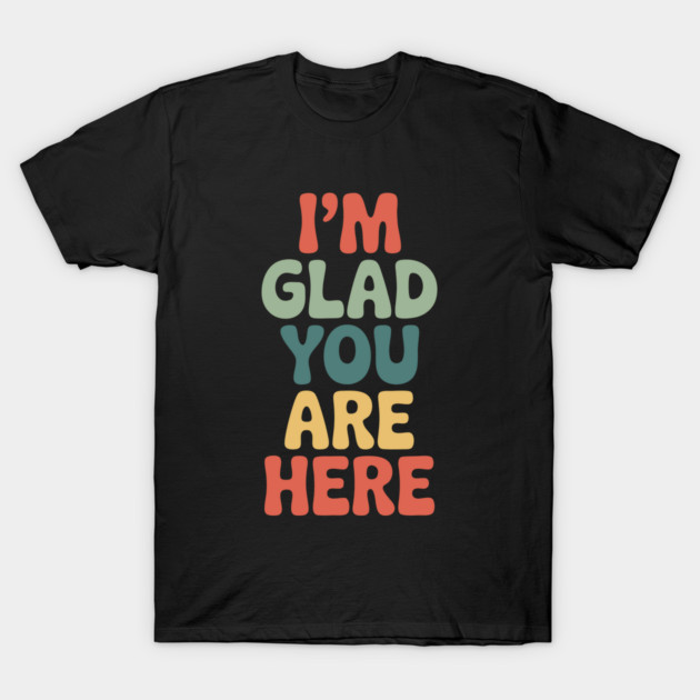 Black T-shirt with colorful "I'm Glad You Are Here" text design, casual and comfortable cotton material.