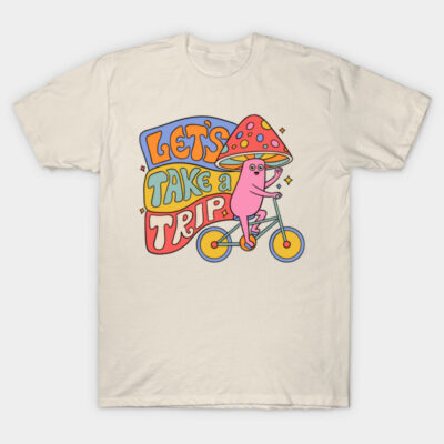Cream T-shirt with colorful "Let's Take a Trip" graphic, featuring a whimsical character riding a bicycle. 100% cotton.