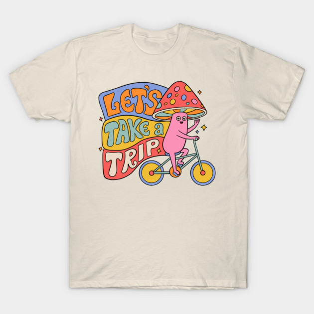 Cream T-shirt with colorful "Let's Take a Trip" graphic, featuring a whimsical character riding a bicycle. 100% cotton.