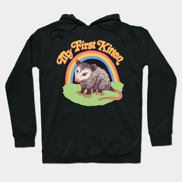 Black hoodie with "My First Kitten" text, featuring a possum and rainbow graphic. Casual style, cozy material.