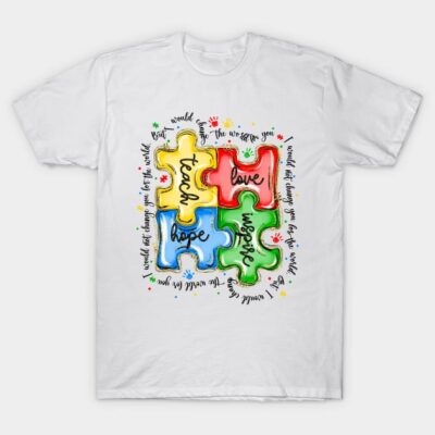 White t-shirt with colorful puzzle design featuring words "teach," "love," "hope," "inspire," ideal for casual wear.