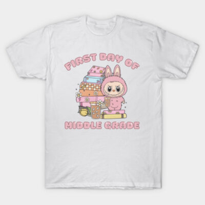 White T-shirt with "First Day of Middle Grade" pink text and cartoon design, featuring books and character in pink outfit.