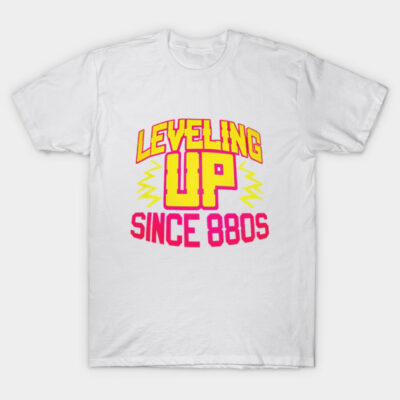 White cotton T-shirt with bold graphic text "Leveling Up Since 80s" in vibrant yellow and pink, perfect for casual wear.