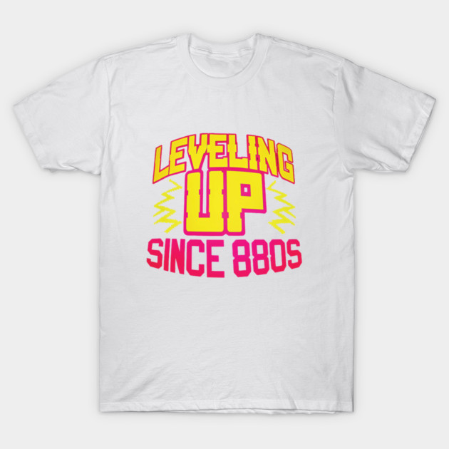 White cotton T-shirt with bold graphic text "Leveling Up Since 80s" in vibrant yellow and pink, perfect for casual wear.