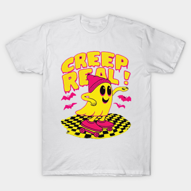 White t-shirt with "Creep Real" text, featuring a yellow ghost on a skateboard, wearing a pink beanie, casual style.