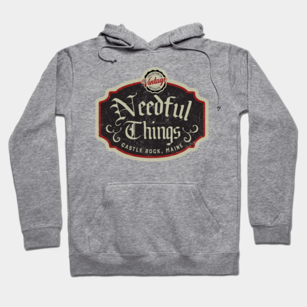 Gray hoodie with "Needful Things" vintage design, featuring front pocket and drawstrings, ideal for casual wear.
