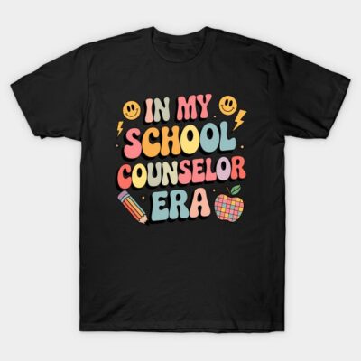 Black T-shirt with colorful "In My School Counselor Era" text, featuring smiley faces, pencil, and apple graphics.