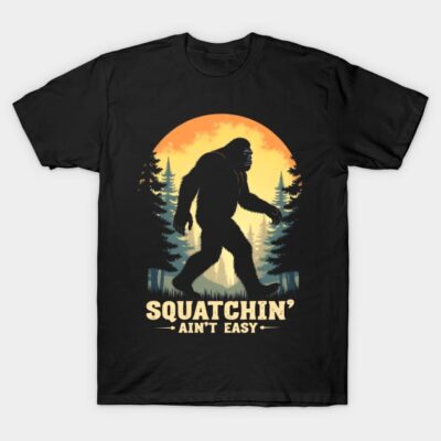 Black t-shirt with Bigfoot silhouette, forest background, and "Squatchin' Ain't Easy" text, casual wear cotton fabric.
