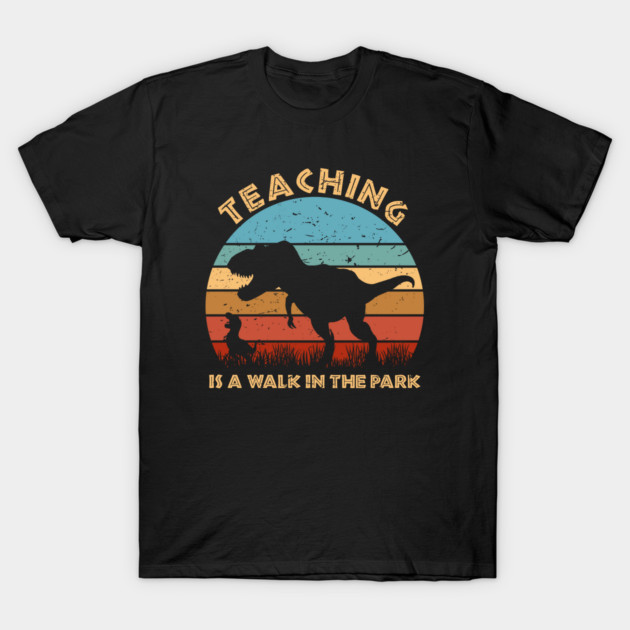 Black t-shirt with retro dinosaur graphic and "Teaching is a Walk in the Park" text, perfect for casual wear.