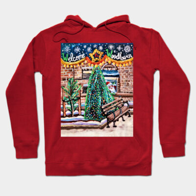 Red hoodie with festive "Welcome to Woodhaven" design, featuring Christmas trees and benches, perfect for winter wear.