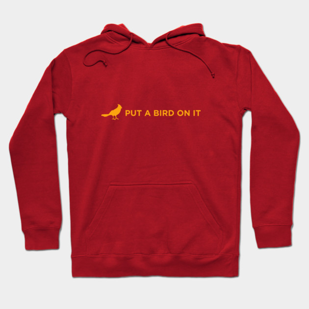 Red hoodie with yellow bird graphic and "Put a Bird on It" text, cotton material, casual style, unisex design.