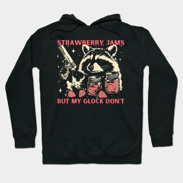 Black hoodie with raccoon design, holding jars and text "Strawberry Jams, But My Glock Don't," casual wear, cotton blend.